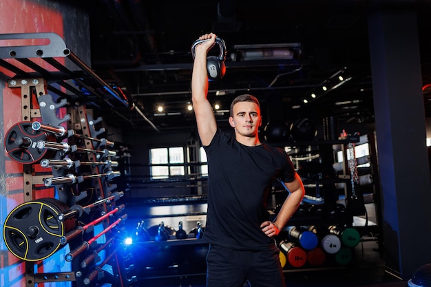 Attractive adult man doing exercises and lifting weights in the gym. Sports training in the gym