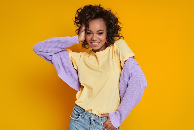 Attractive African woman smiling while standing against yellow background