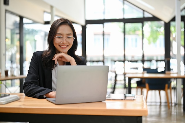 Attractive Asian businesswoman thinking a business strategy for new campaign using laptop