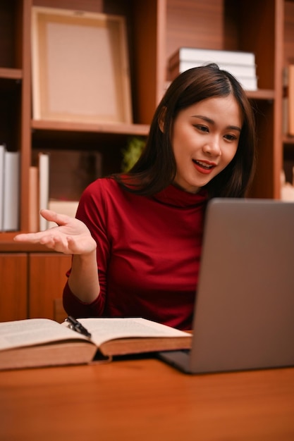 Attractive Asian businesswoman using laptop having an online meeting conference with her team