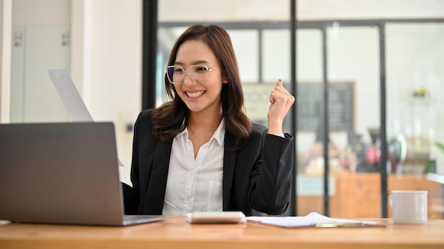 Attractive Asian businesswoman working at her desk looking at her laptop screen