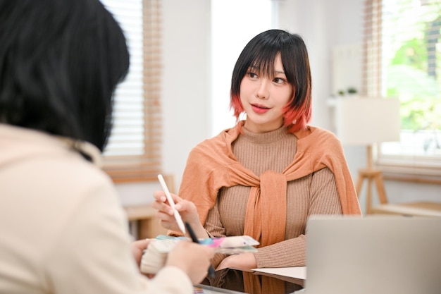 Attractive Asian female graphic designer discussing and working with her colleagues