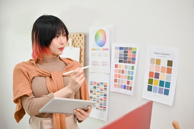 Attractive Asian female graphic designer working on her new design project in her studio