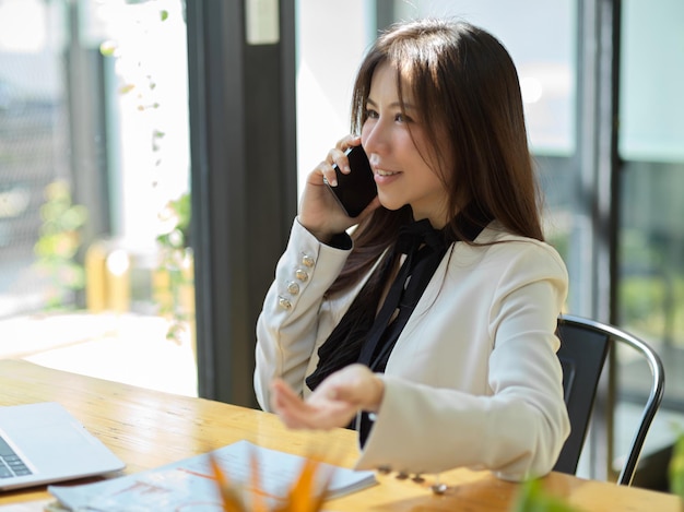 An attractive Asian female manager has a business deal on her cellphone. Woman talking on the phone.