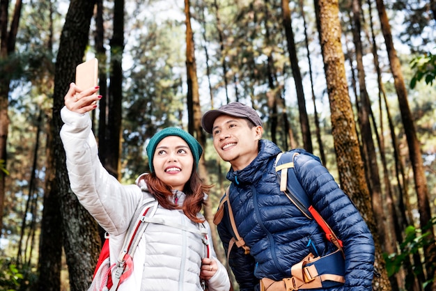 Attractive asian hikers couple taking selfie photo with mobile phone