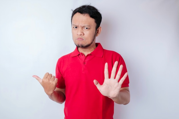 Attractive Asian man with hand gesture pose rejection or prohibition while pointing to copy space by his side