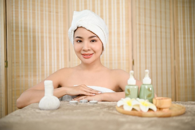 Attractive Asian woman in bathrobe with herbal massage ball treatment body oil bottle