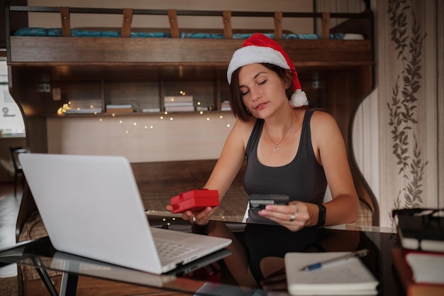 Attractive asian woman holding a credit card and shopping on a laptop