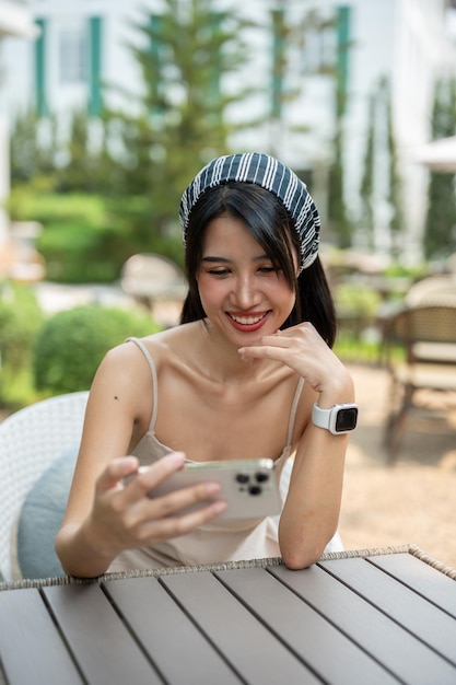 An attractive Asian woman watching videos on her smartphone while sitting in a beautiful garden