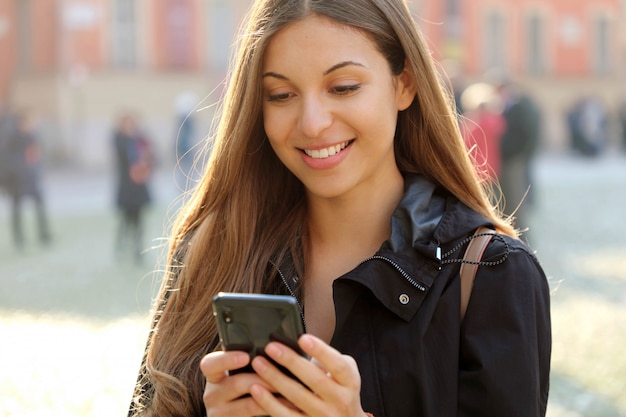 Attractive beautiful young woman using smart phone outdoors in the city