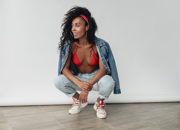 Attractive black african american woman posing in stylish hipster outfit on white background