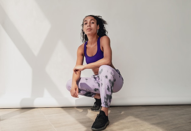 Attractive black african american woman in stylish hipster fitness outfit on background