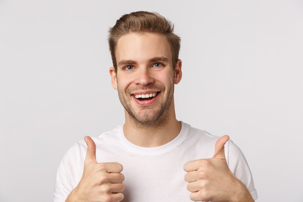 Attractive blond bearded man in white T-shirt giving thumbs up