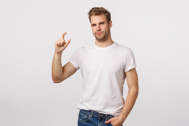 Attractive blond bearded man in white T-shirt making tiny gesture