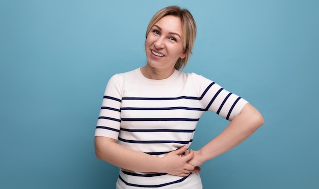 Attractive blond young woman in green silk shirt laughing on blue background