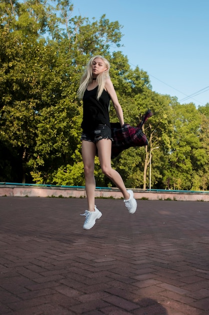 Attractive blonde woman with beautiful long legs jumping in the park