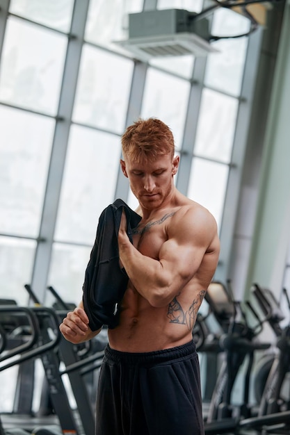 Attractive Bodybuilder Taking His Shirt Off After Training In A Gym