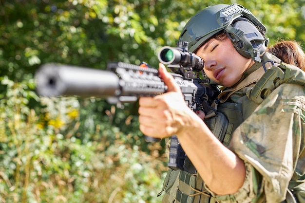 Attractive brave military woman with a gun in forest, survival in wild forest