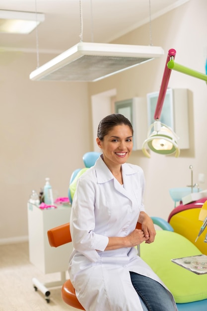 Attractive browneyed dentist sitting on an orange chair