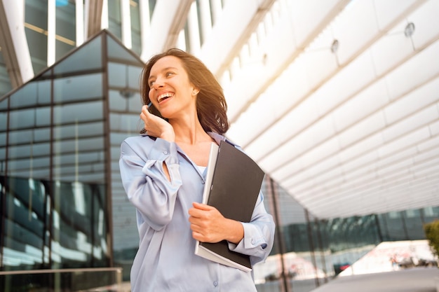 Attractive brunette businesswoman talking mobile phone with client Pretty caucasian female business person smile when phone conversation