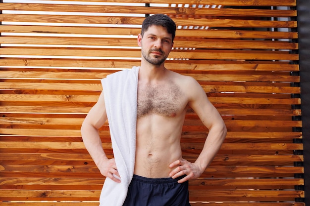 Attractive brunette man with a naked torso and a towel on his shoulder