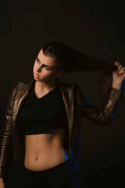 Attractive brunette  model in leather jacket pulling her hair