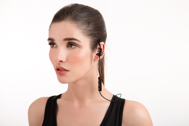 Attractive brunette woman in jogging black top listening to music on earphones posing isolated on white background ponytail hairstyle