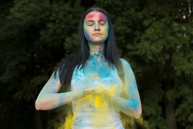 Attractive brunette woman playing with colored powder