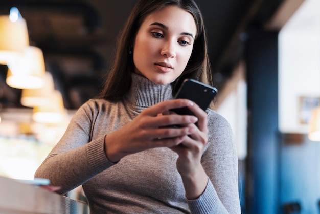 Attractive business woman sits at table in front of laptop and talks on mobile phone, negotiates on the phone.