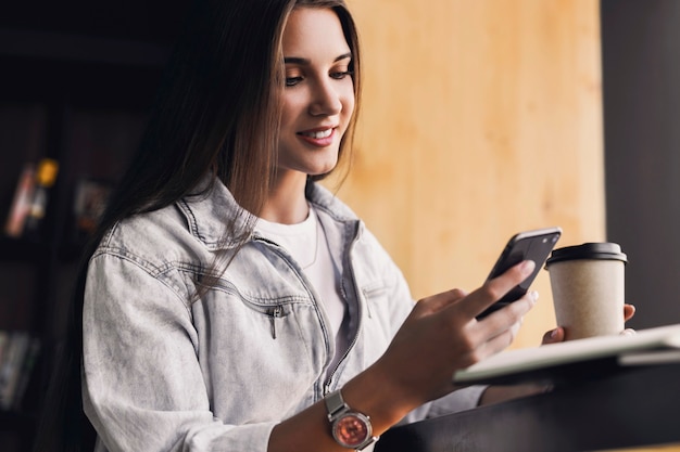 Attractive business woman sits at table in front of laptop and talks on mobile phone, negotiates on the phone.