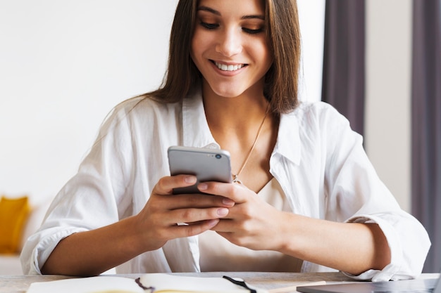 Attractive business woman sits at table in front of laptop and talks on mobile phone, negotiates on the phone.