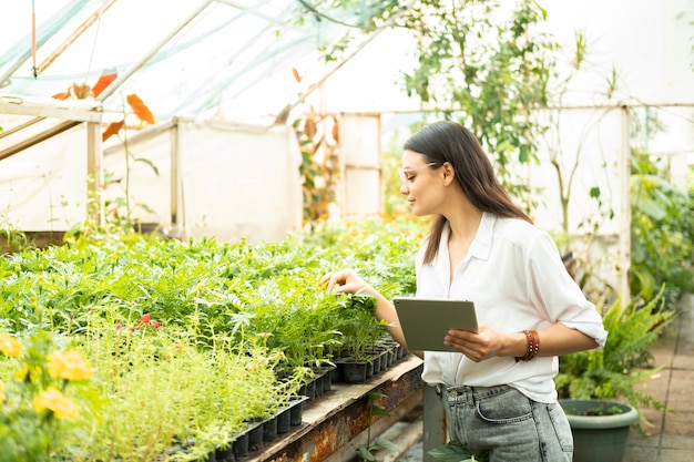 Attractive business women gardener in glasses using tablet modern technology in gardening business