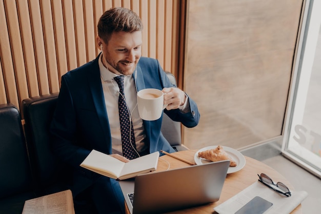 Attractive businessman remotely working online while sitting in coffee shop