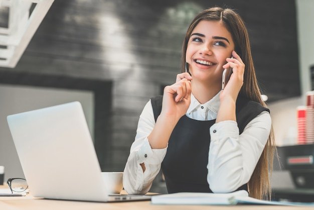 The attractive businesswoman phones near the modern laptop