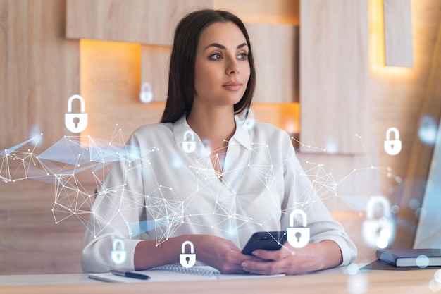 Attractive businesswoman in white shirt checking cyber security using smart phone to protect clients confidential information IT hologram lock icons over modern office background