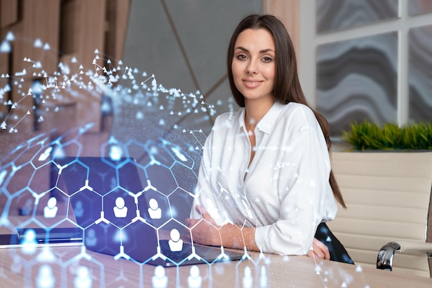 Attractive businesswoman in white shirt at workplace working with laptop to hire new employees for international business consulting HR social media hologram icons over office background