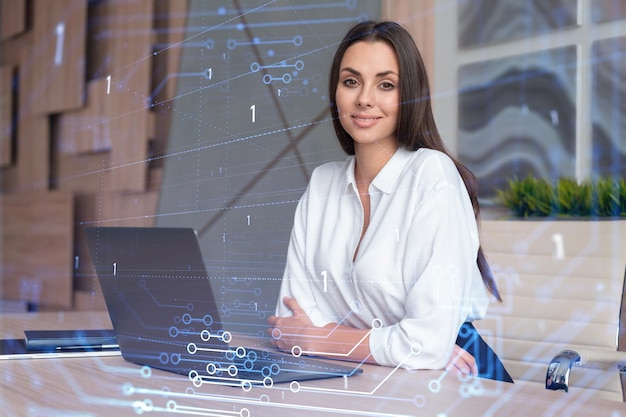 Attractive businesswoman in white shirt at workplace working with laptop to optimize development by implying new technologies in business process Hi tech hologram over office background