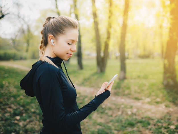 Attractive caucasian girl on yellow isolated background with wireless headphones in sport suit make workout run and drinking water