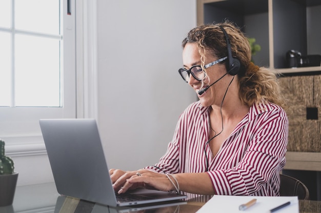 Attractive caucasian woman sit at home office room wearing headset take part in educational webinar using laptop Video call event with clients or personal chat with friend remotely conceptxA