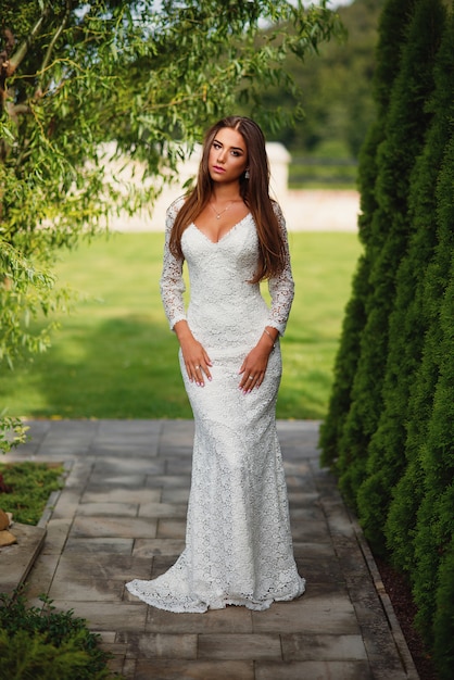 Attractive charming bride in white lace dress with green grass 