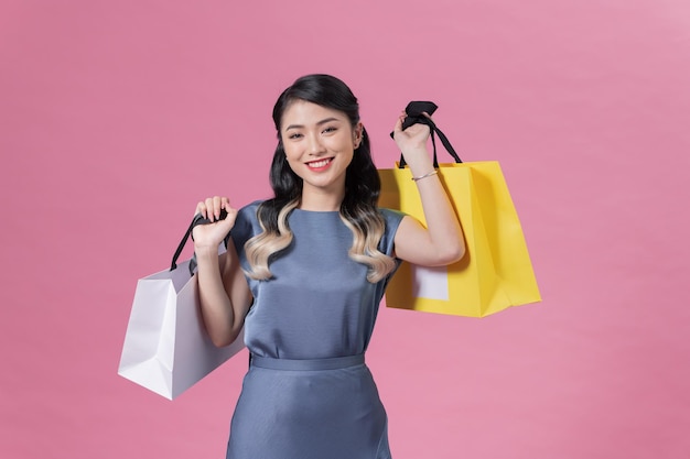 Attractive cheerful girl holding buyings consumerism isolated over pink color background