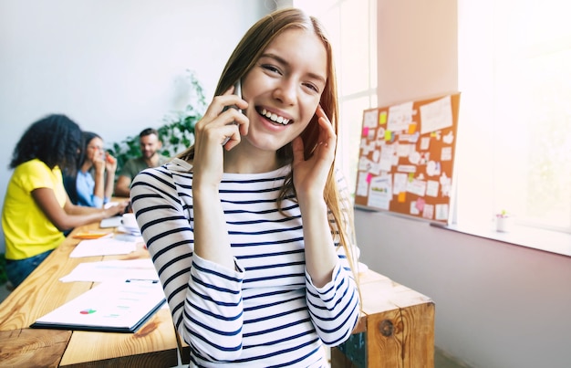 Attractive confident modern business woman in casual clothes looks at the camera and smiling. Modern start-up business team. Co-workers or students