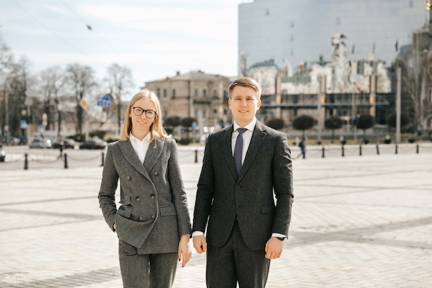 An attractive couple of businessmen in strict office suits in the city