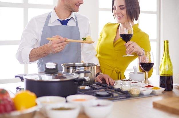 Attractive couple in love cooking and opens the wine in the kitchen while they cook dinner for a romantic evening