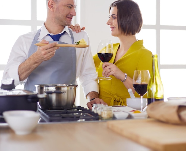 Attractive couple in love cooking and opens the wine in the kitchen while they cook dinner for a romantic evening