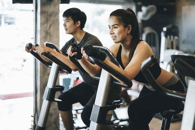 Attractive couple riding on the spinning bike at gym. Working out together 