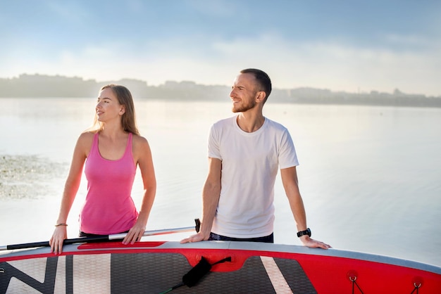 Attractive couple standing with sup board concept of active life