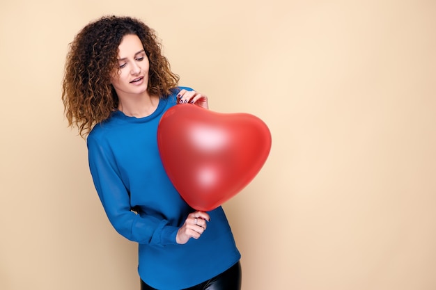 Attractive curly hair woman holding red heart shape balloon