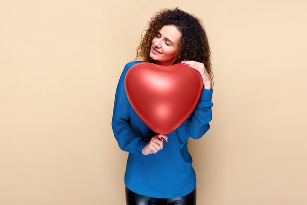 Attractive curly hair woman holding red heart shape balloon