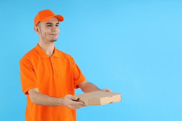 Attractive delivery man with pizza box on blue background